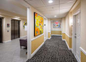 Thumbnail 3 of 11 - A hallway with a large painting on the wall and a bench on the floor.
