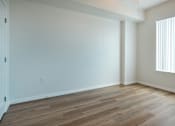 Thumbnail 4 of 30 - A room with wooden flooring and a window with blinds.
