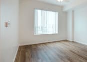 Thumbnail 3 of 30 - A room with a window and wooden flooring.