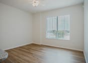 Thumbnail 8 of 30 - Empty room with a window and wooden floor.