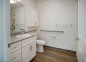 Thumbnail 16 of 30 - A white bathroom with a toilet, sink, and grab bars.