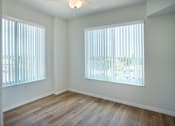 Thumbnail 14 of 30 - A room with wooden floors and two windows with blinds.