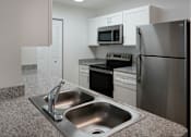 Thumbnail 12 of 30 - A modern kitchen with a stainless steel refrigerator, microwave, and oven.