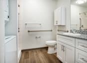 Thumbnail 20 of 30 - A white bathroom with a toilet, sink, and a mirror.