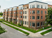 Thumbnail 4 of 13 - A row of modern apartment buildings with a clear sky above.