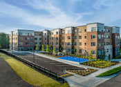 Thumbnail 7 of 13 - A row of modern apartment buildings with a playground in the foreground.