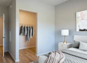 Thumbnail 9 of 13 - A bedroom with a bed, nightstand, and clothes hanging on a rack.
