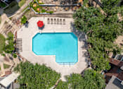 Thumbnail 10 of 35 - A red umbrella sits on the edge of a blue swimming pool.