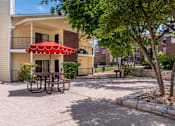 Thumbnail 12 of 35 - A red umbrella is on a table in the courtyard of a building.