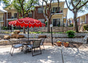 Thumbnail 9 of 35 - A patio with a table and chairs and a red umbrella.