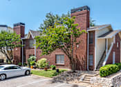 Thumbnail 19 of 35 - A house with a red brick exterior and a white car parked in front.