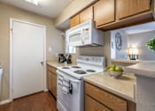 Thumbnail 26 of 35 - A kitchen with a white stove and a white door.