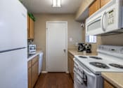 Thumbnail 25 of 35 - A white refrigerator is in a kitchen with a white door and a white stove.