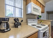Thumbnail 20 of 35 - A kitchen with a white stove top oven and a white microwave above it.