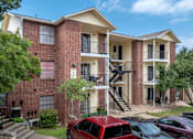 Thumbnail 17 of 35 - A red car is parked in front of a brick apartment building.