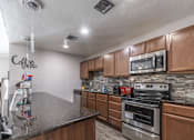Thumbnail 30 of 35 - A kitchen with a granite countertop and wooden cabinets.