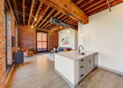 Thumbnail 1 of 41 - a kitchen with a white counter top in a room with a exposed brick wall at Greeley Lofts, St. Louis, Missouri