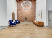 Thumbnail 23 of 41 - a living room with blue chairs and a brick wall at Greeley Lofts, St. Louis, MO