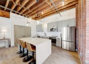 Thumbnail 5 of 41 - a kitchen with a white island and a stainless steel refrigerator at Greeley Lofts, Missouri