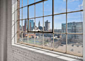 Thumbnail 10 of 58 - A view of a city skyline through a window with a brick wall on the left.