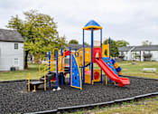Thumbnail 10 of 18 - A playground with a red slide and a blue and yellow structure.