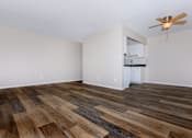 Thumbnail 3 of 23 - an empty living room with a ceiling fan and a kitchen in the background