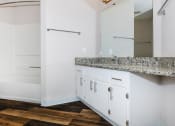 Thumbnail 13 of 31 - a bathroom with white cabinets and a wooden floor