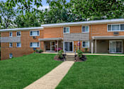 Thumbnail 16 of 23 - a brick building with a green lawn and trees in the background