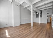 Thumbnail 7 of 58 - A spacious room with wooden floors and white walls.