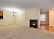 Thumbnail 22 of 27 - A living room with a fireplace and a chandelier.
