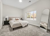 Thumbnail 7 of 44 - A bedroom with a large bed and a window overlooking a tree-lined street. at Park Lamont Townhomes Apartments, Ohio, 44106