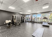 Thumbnail 31 of 61 - A spacious gym with a variety of equipment and a view of trees outside the window.