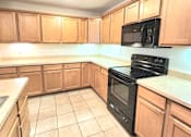 Thumbnail 20 of 27 - A kitchen with wooden cabinets and a black stove top oven.