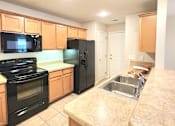 Thumbnail 19 of 27 - A kitchen with black appliances and wooden cabinets.