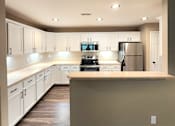 Thumbnail 13 of 27 - A kitchen with white cabinets and a refrigerator.