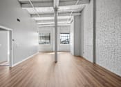 Thumbnail 9 of 58 - A long, empty room with white walls and wooden floors.