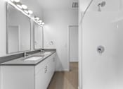 Thumbnail 10 of 61 - A white bathroom with a sink, mirrors, and a shower.