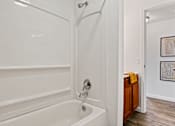 Thumbnail 7 of 19 - A white bathtub with a shower head and a wooden cabinet. at Vivo Toledo Apartments, Toledo, 43607