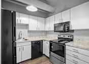 Thumbnail 28 of 58 - A black refrigerator is in a kitchen with white cabinets and a marble countertop.