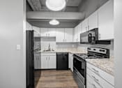 Thumbnail 29 of 58 - A modern kitchen with black and white appliances and cabinets.