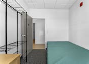 Thumbnail 7 of 61 - A room with a bed, a desk, and a metal shelving unit.