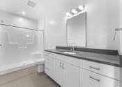 Thumbnail 13 of 61 - A white bathroom with a sink, mirror, and shower.