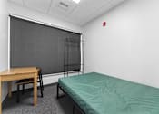 Thumbnail 11 of 61 - A room with a bed, desk, chair, and a blackboard.