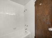 Thumbnail 40 of 48 - a white bathroom with a white tub and a wooden door