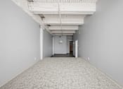 Thumbnail 31 of 58 - A long, empty hallway with a carpeted floor and white walls.