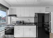 Thumbnail 1 of 61 - A modern kitchen with white cabinets and black countertops.