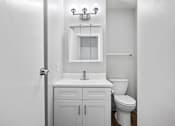 Thumbnail 26 of 58 - A white bathroom with a toilet, sink, and mirror.