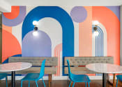 Thumbnail 2 of 48 - a restaurant with blue chairs and tables and a colorful wall with arches