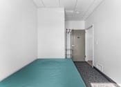Thumbnail 18 of 61 - A room with a blue mattress and a metal gate.