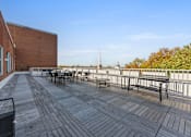 Thumbnail 47 of 61 - A wooden deck with benches and a table is surrounded by a metal fence.
